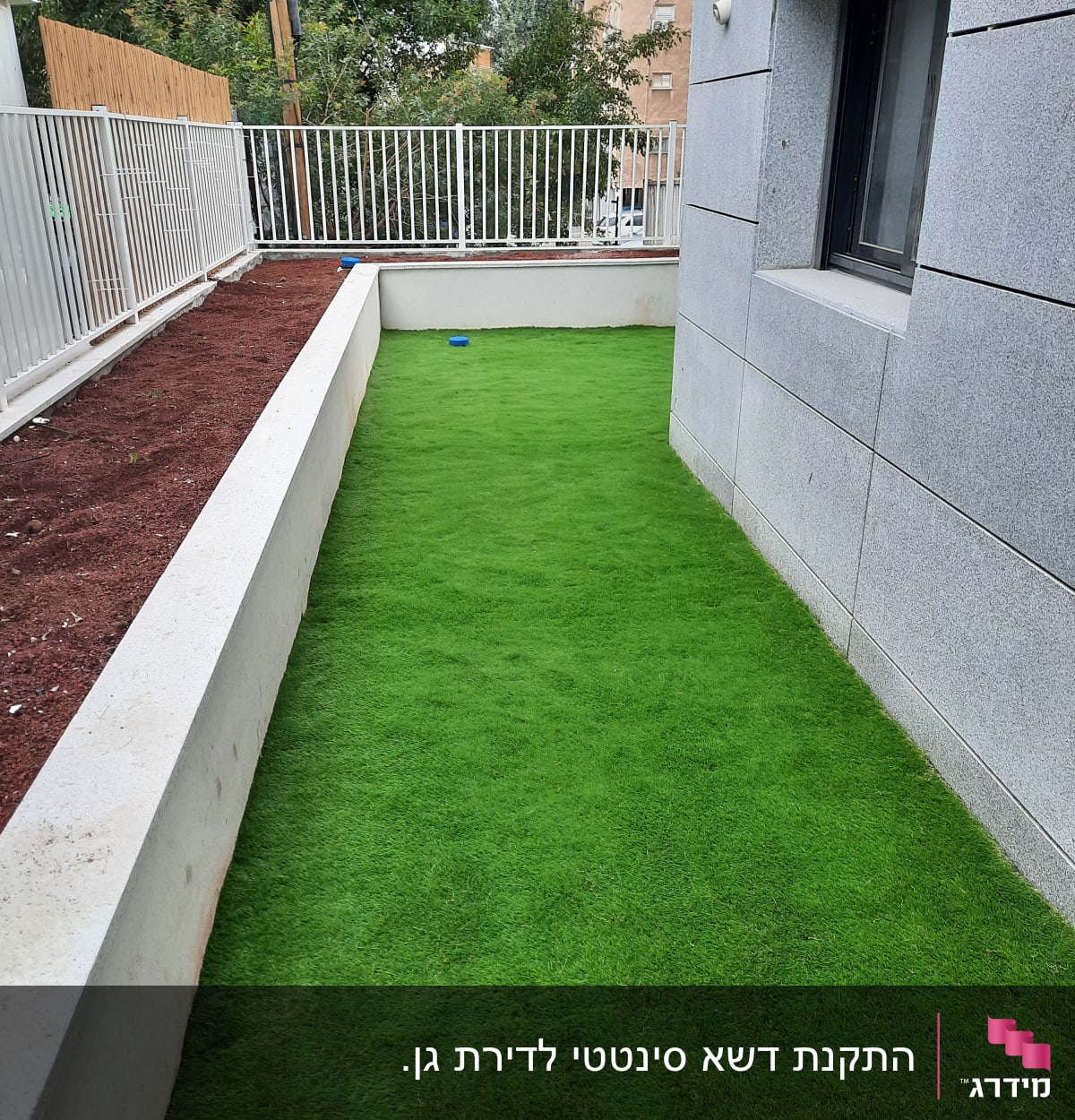 דשא סינתטי וערוגת אדמה לצד גדר לבנה